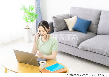 A woman calling on her smartphone while teleworking at home 77832976