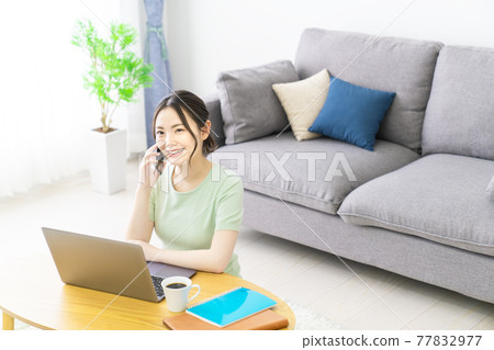 A woman calling on her smartphone while teleworking at home 77832977
