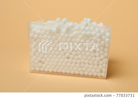 Plastic box with cotton swabs on beige background 77833731