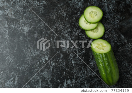 Ripe cucumber and slices on black smoky background Ripe cucumber and slices on black smoky background 77834159