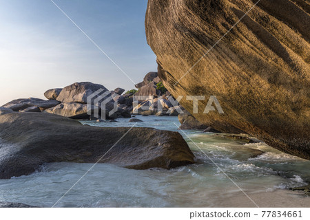 The sea washing the coastal boulders and rocks at sunset The sea washing the coastal boulders and rocks at sunset 77834661