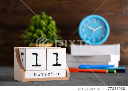 November 11th. November 11 wooden cube calendar with blur objects on background. 77835088