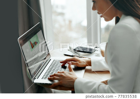Businesswoman working on laptop computer managing her business via office Businesswoman working on laptop computer managing her business via office 77835538