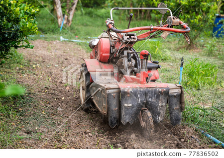 Tractor shoveling the soil in plantation 77836502