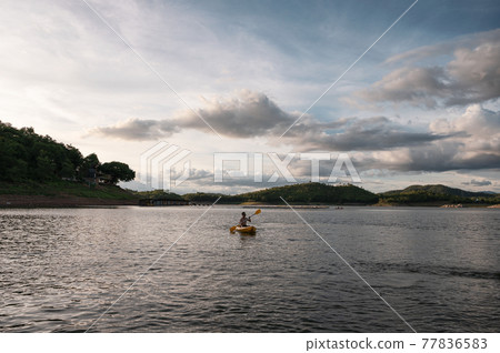 Tourist man canoeing on lake in national park at evening 77836583