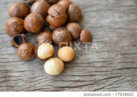 Organic Macadamia nuts with shell on wood table 77836602