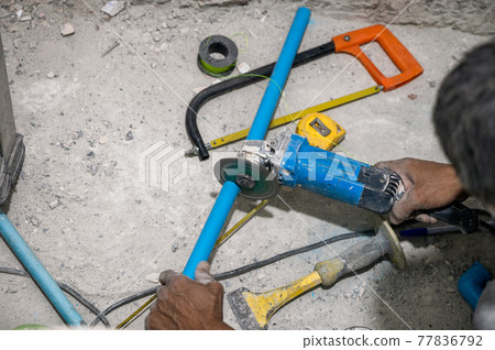 Plumber using electric saw cutting pvc pipe during renovation 77836792