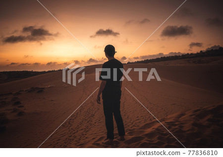 Traveler man with cap standing on dune at sunset Traveler man with cap standing on dune at sunset 77836810