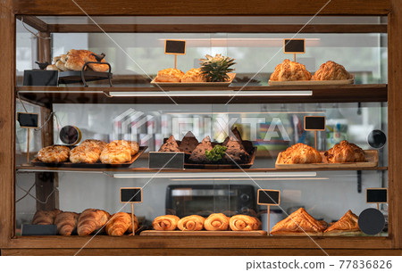 Variety baked bread and dessert in glass showcase at bakery 77836826