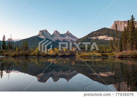 Three sisters mountains of rocky mountains reflection on bow river in the morning at Canmore, Banff national park Three sisters mountains of rocky mountains reflection on bow river in the morning at Canmore, Banff national park 77836876