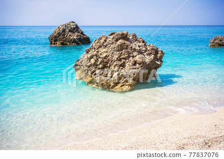 Beautiful sandy beach with turquoise water and big rocks 77837076