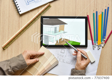 a top view of architect working desk with hand work point to color chart with equipment for drawings sketched on wood table, the concept of modern technology for architectural working with tablet a top view of architect working desk with hand work point to color chart with equipment for drawings sketched on wood table, the concept of modern technology for architectural working with tablet 77837400