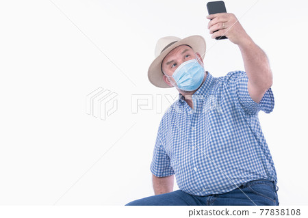 Man with face mask taking a photo of himself: Selective focus. Lifestyle and photography concept. Man with face mask taking a photo of himself: Selective focus. Lifestyle and photography concept. 77838108