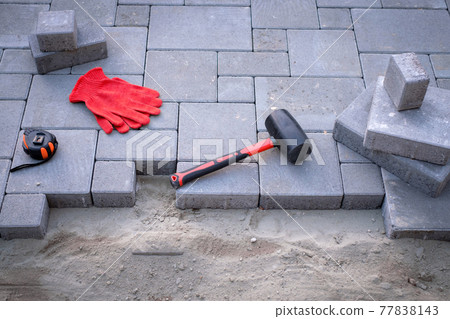 The master in yellow gloves lays paving stones 77838143
