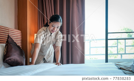 Hotel maid making the bed in the luxury hotel room ready for tourist travel Hotel maid making the bed in the luxury hotel room ready for tourist travel 77838283