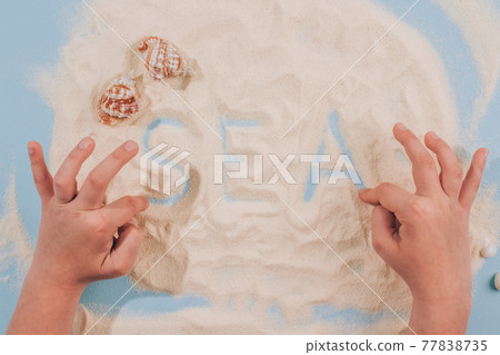 Child's hands playing with sea shells and sand - Montessori education concept. Fine motoric skills or attention training exercises. Educational toys, cognitive and motor development Child's hands playing with sea shells and sand - Montessori education concept. Fine motoric skills or attention training exercises. Educational toys, cognitive and motor development 77838735