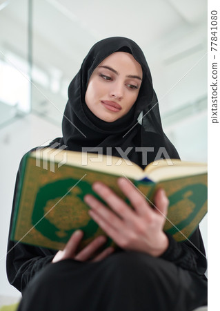 Portrait of young muslim woman reading Quran in modern home Portrait of young muslim woman reading Quran in modern home 77841080