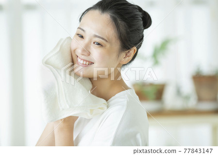 一位年輕的女士用毛巾擦臉 77843147