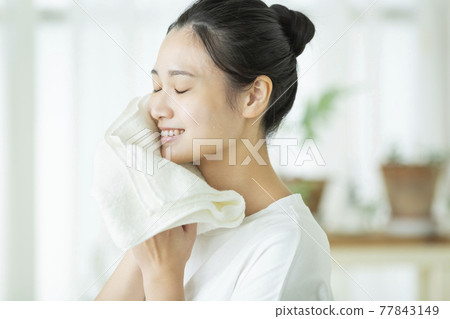 一位年輕的女士用毛巾擦臉 一位年輕的女士用毛巾擦臉 77843149
