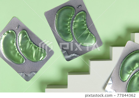 Eye patches on stairs over green backgound. Face care beauty treatment steps concept Eye patches on stairs over green backgound. Face care beauty treatment steps concept 77844362