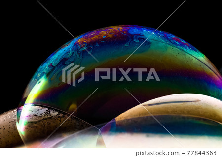 Close up of three stacked soap bubbles with rainbow colours and patterns Close up of three stacked soap bubbles with rainbow colours and patterns 77844363