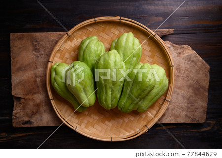Chayote squash fruit (Mirliton, pipinola or choko) in a basket on wooden background 77844629
