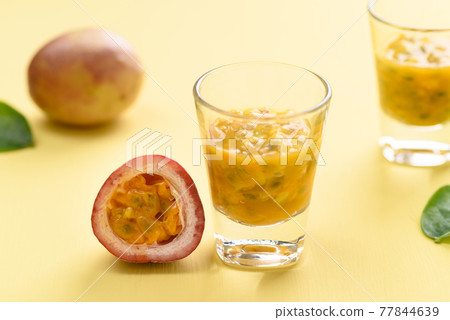 Fresh passion fruit juice in glass on yellow background Fresh passion fruit juice in glass on yellow background 77844639