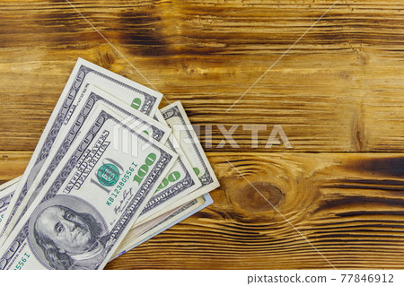 Stack of one hundred dollars bills on wooden desk Stack of one hundred dollars bills on wooden desk 77846912