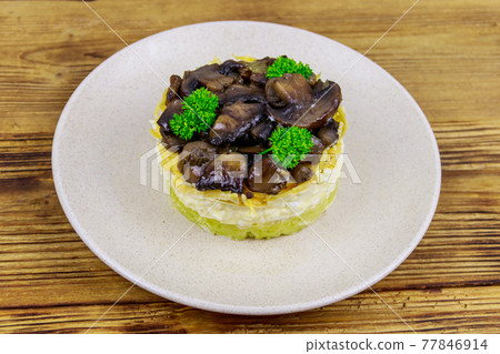Tasty layered salad with roasted mushrooms, potato, eggs, cheese and mayonnaise on wooden table 77846914