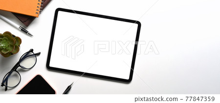 Mock up digital tablet with blank screen, glasses, notebook and mobile phone on white desk. 77847359