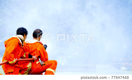 Firefighter fighting with flame using fire hose chemical water foam spray engine. Fireman wear hard hat, body safe suit uniform for protection. Rescue training in fire fighting extinguisher Firefighter fighting with flame using fire hose chemical water foam spray engine. Fireman wear hard hat, body safe suit uniform for protection. Rescue training in fire fighting extinguisher 77847488