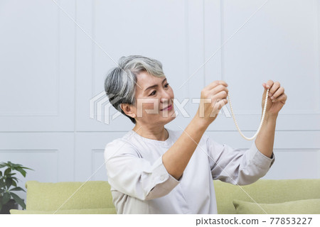 Elegant silver-haired man wearing pearl necklace Elegant silver-haired man wearing pearl necklace 77853227