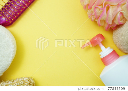 Flat lay bath products shower bottle with shower puff and hair brush on yellow background Flat lay bath products shower bottle with shower puff and hair brush on yellow background 77853509