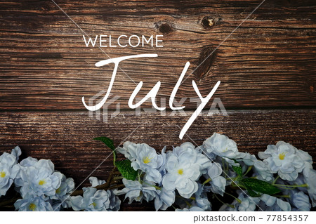 Welcome July text and blue flower decoration on wooden background Welcome July text and blue flower decoration on wooden background 77854357