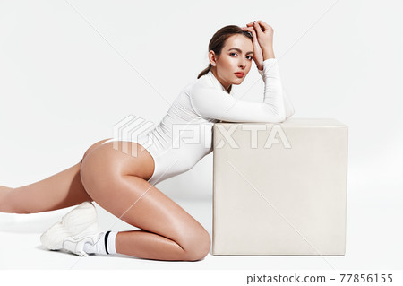 Sexy sporty woman in white bodysuit posing on white studio background 77856155