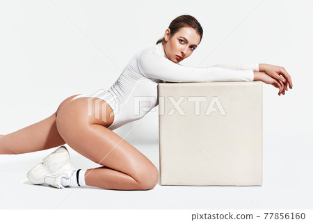 Sexy sporty woman in white bodysuit posing on white studio background 77856160