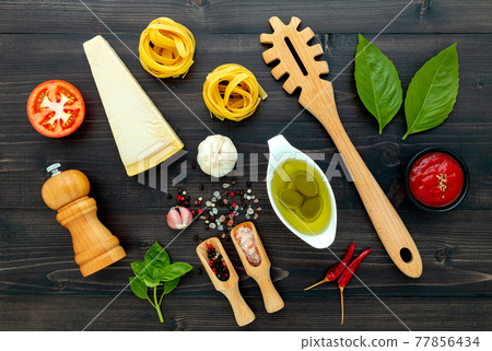 The pasta on black wooden background. Yellow italian pasta with ingredients. Italian food and menu concept. The pasta on black wooden background. Yellow italian pasta with ingredients. Italian food and menu concept. 77856434