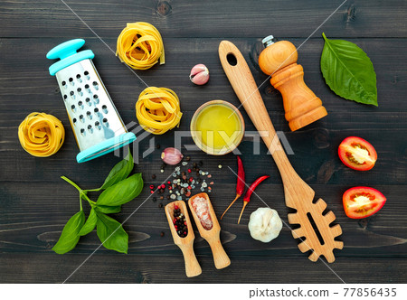 The pasta on black wooden background. Yellow italian pasta with ingredients. Italian food and menu concept. The pasta on black wooden background. Yellow italian pasta with ingredients. Italian food and menu concept. 77856435