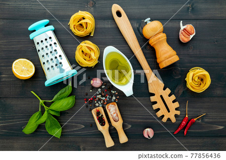 The pasta on black wooden background. Yellow italian pasta with ingredients. Italian food and menu concept. The pasta on black wooden background. Yellow italian pasta with ingredients. Italian food and menu concept. 77856436