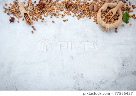 Roasted coffee beans with scoops setup on white concrete background. 77856437