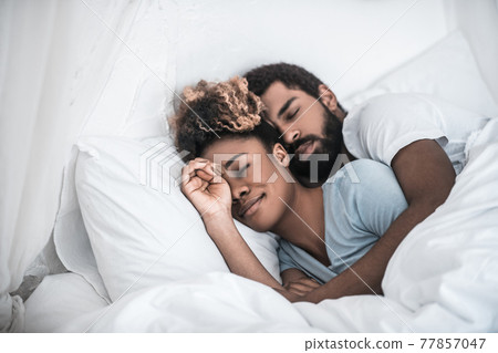 Man hugging his wife sleeping in bedroom 77857047