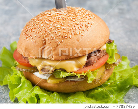 Burger with beef, pickles, tomatoes and cheese. Close up 77857459