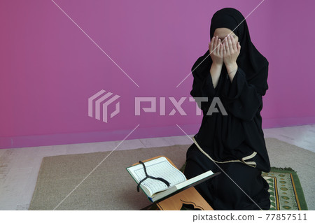 Middle eastern woman praying and reading the holy Quran 77857511
