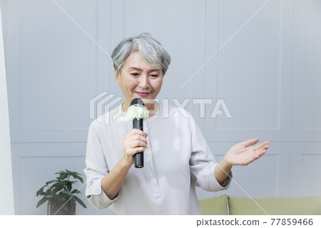 Elderly lady singing with a microphone 77859466