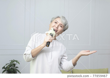 Elderly lady singing with a microphone 77859467