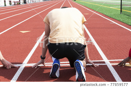 Sprinter on his mark at the starting line from behind 77859577