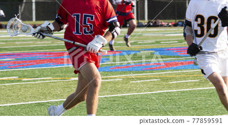 Lacrosse player running up the fiield with the ball in the netting of his stick 77859591