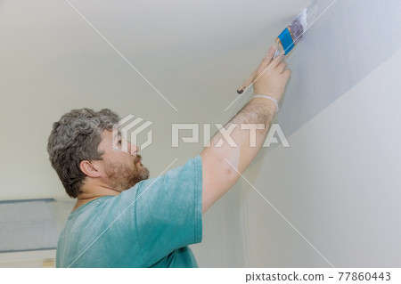 Professional painter using a brush to paint on wall Professional painter using a brush to paint on wall 77860443
