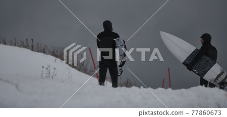 Arctic surfers running on beach after surfing 77860673