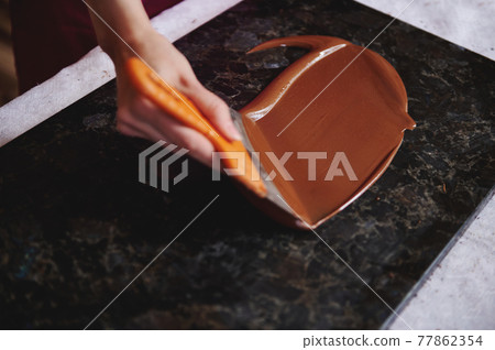 Closeup of woman's hand tempering melted chocolate on a marble surface 77862354